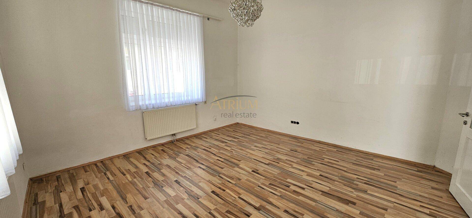 Geräumiger, heller Raum mit Holzboden und Fenster, bereit zur individuellen Gestaltung.