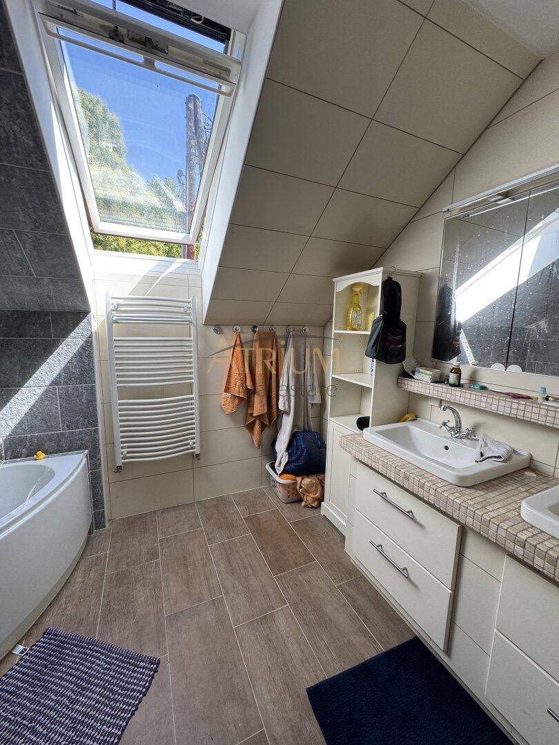 Helles Badezimmer mit Dachfenster, Badewanne und modernem Waschtisch in Dachschräge.