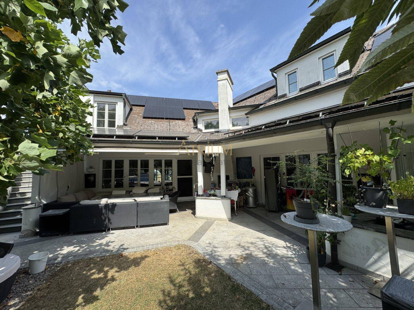 Geräumige Terrasse mit Sitzgelegenheiten und Blick auf den Garten, ergänzt durch Solarpaneele auf dem Dach.