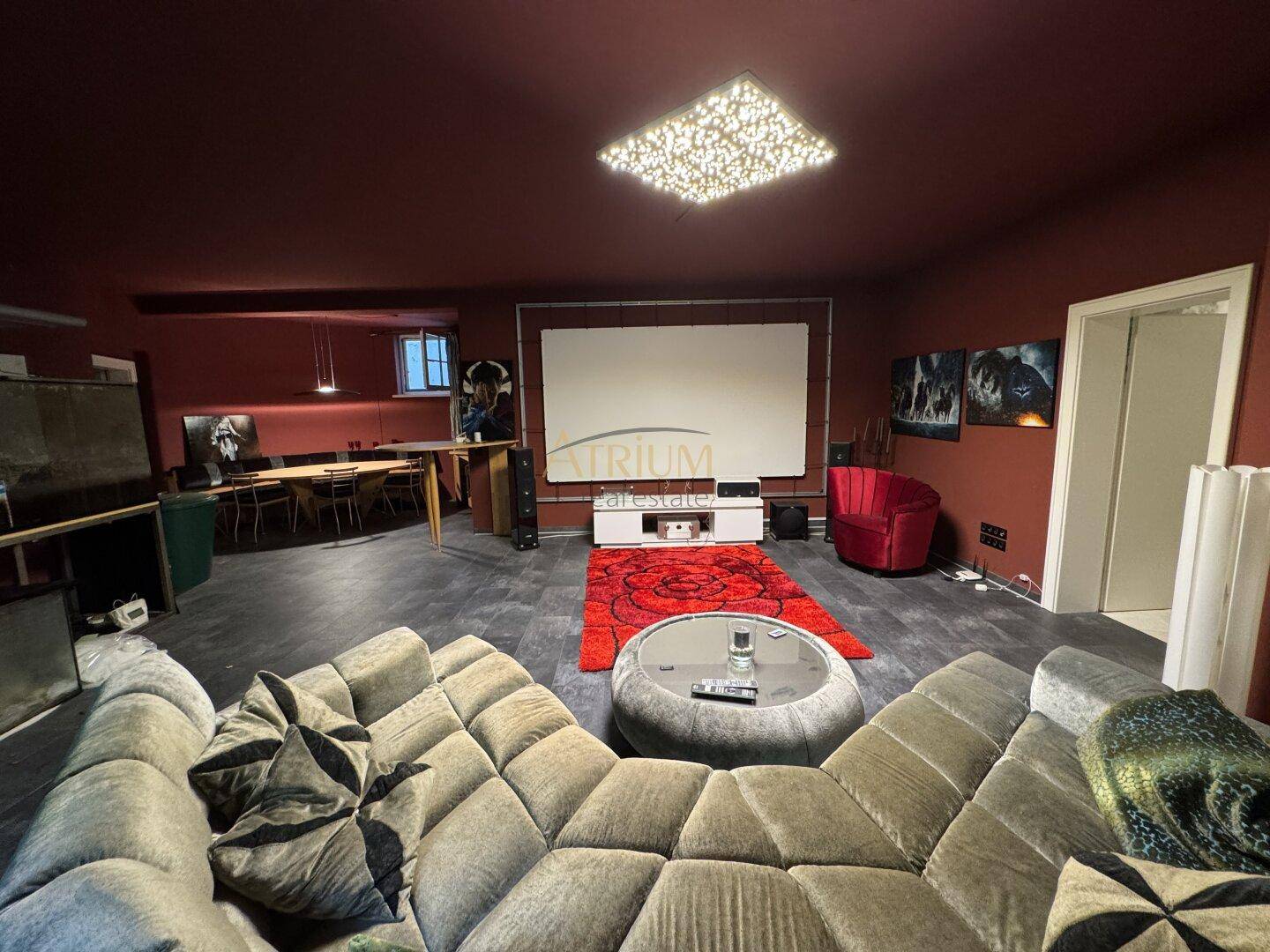 Gemütlicher Medienraum mit großer Leinwand, bequemen Sofas und dunklen Wänden für Kinoabende.