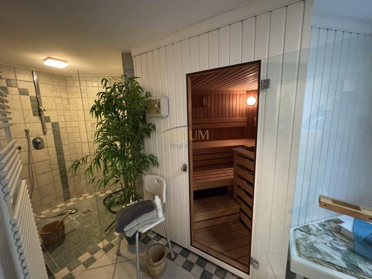 Modernes Badezimmer mit integrierter Sauna, großer Dusche und Fliesenboden für Wellnessmomente.