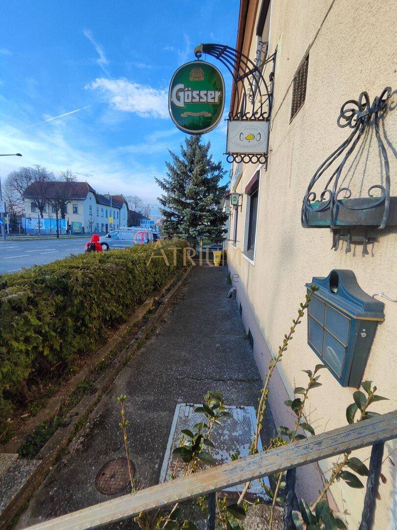 Außenansicht eines Gebäudes mit Werbeschild, Briefkasten und Blick auf die Straße.