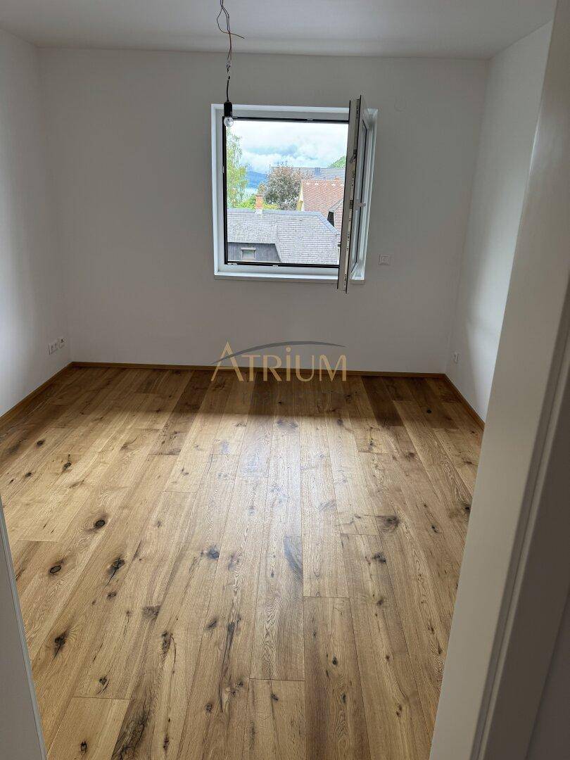 Heller, unmöblierter Raum mit neuem Holzboden und einem Fenster, das viel Tageslicht hereinlässt.
