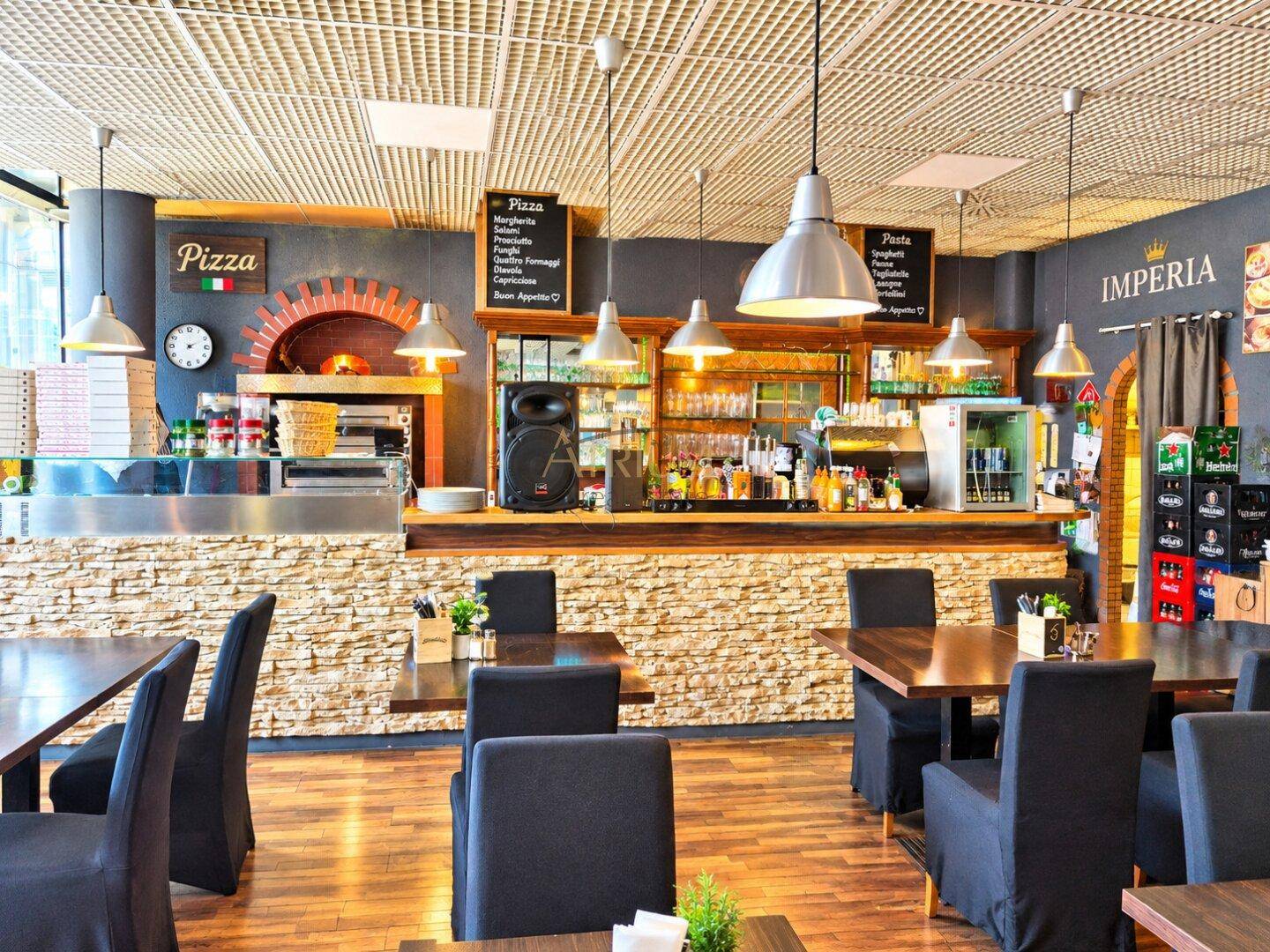 Restaurant-Barbereich mit integriertem Pizzaofen, Steintheke und Holzböden, ergänzt durch moderne Beleuchtung.