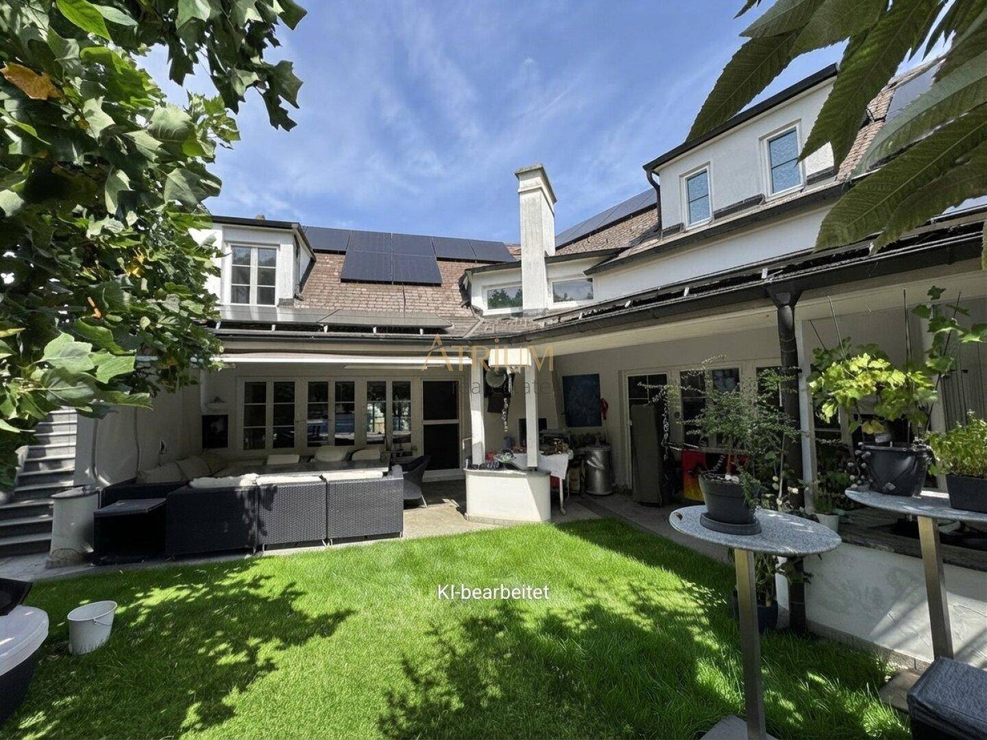 Ruhiger Gartenbereich hinter dem Haus mit Rasenfläche, Sitzgelegenheiten und Solarpaneelen auf dem Dach.