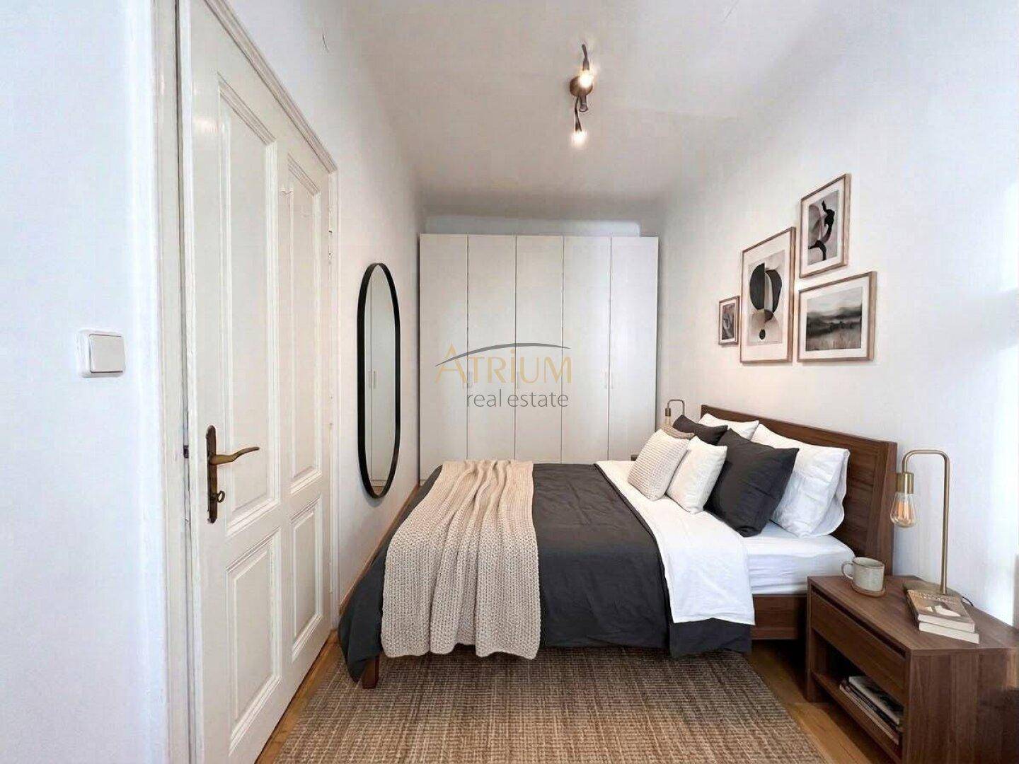 Gemütliches Schlafzimmer mit Doppelbett, Nachttisch, weißem Kleiderschrank und dekorativen Bildern an der Wand.