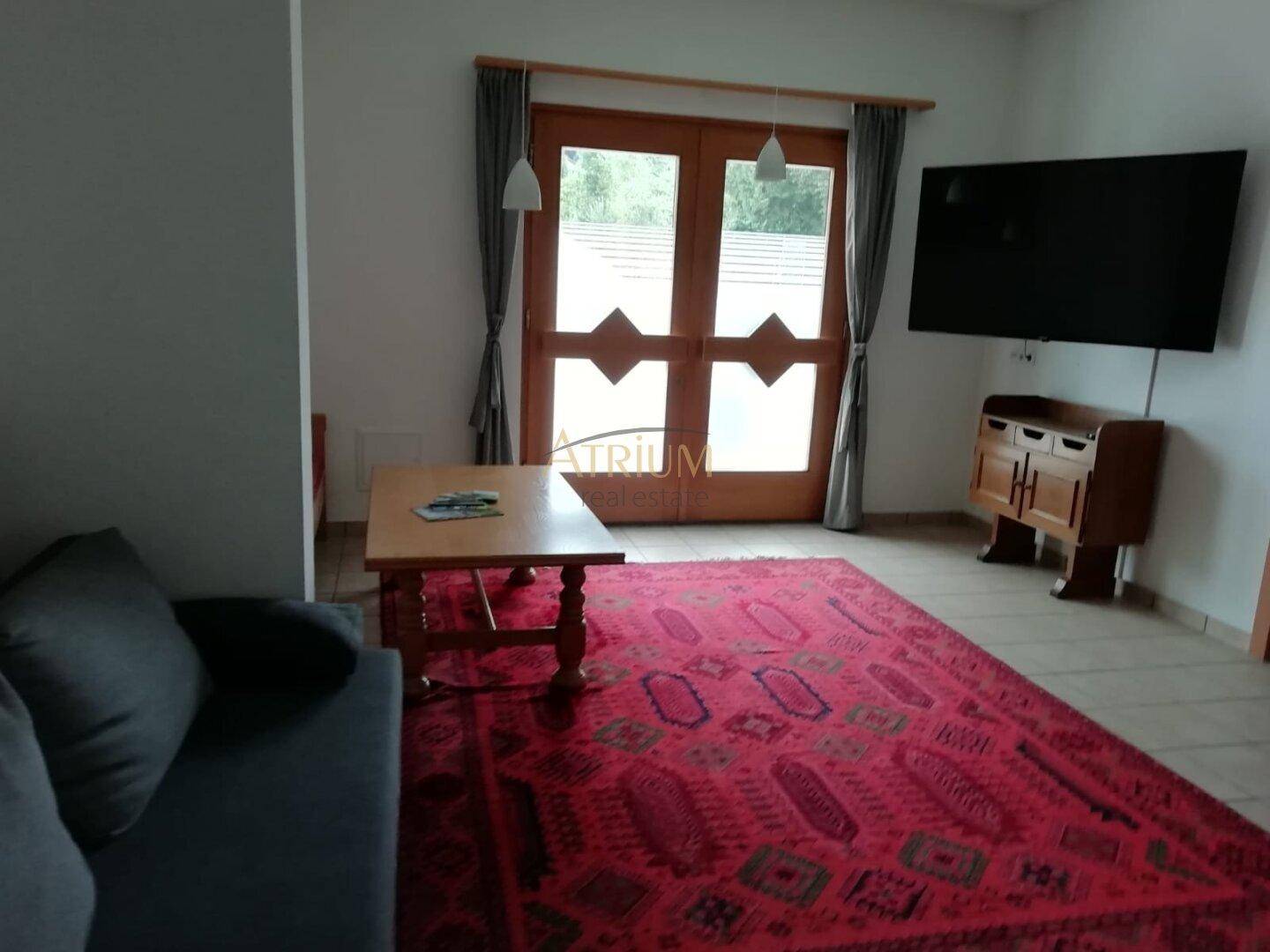 Gemütliches Wohnzimmer mit Sofa, Couchtisch, Fernseher und Zugang zur Terrasse.