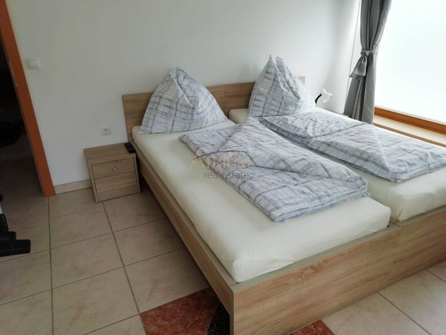 Helles Schlafzimmer mit zwei Einzelbetten, Nachttisch und Fliesenboden.