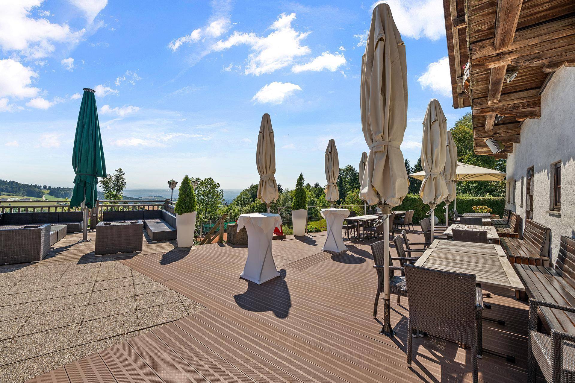 Moderne Außenterrasse mit Holz- und Steinbereichen, Lounge-Möbeln und Sonnenschirmen.
