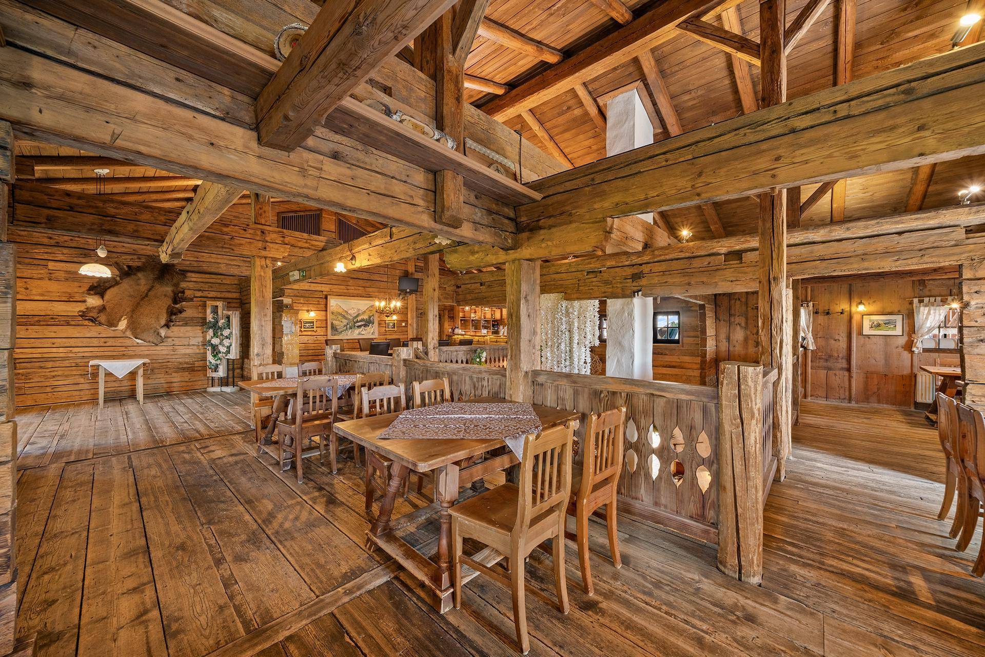 Geräumiger Gastraum mit Holzböden, Holzbalken und traditionellen Holztischen, ideal für größere Gruppen.