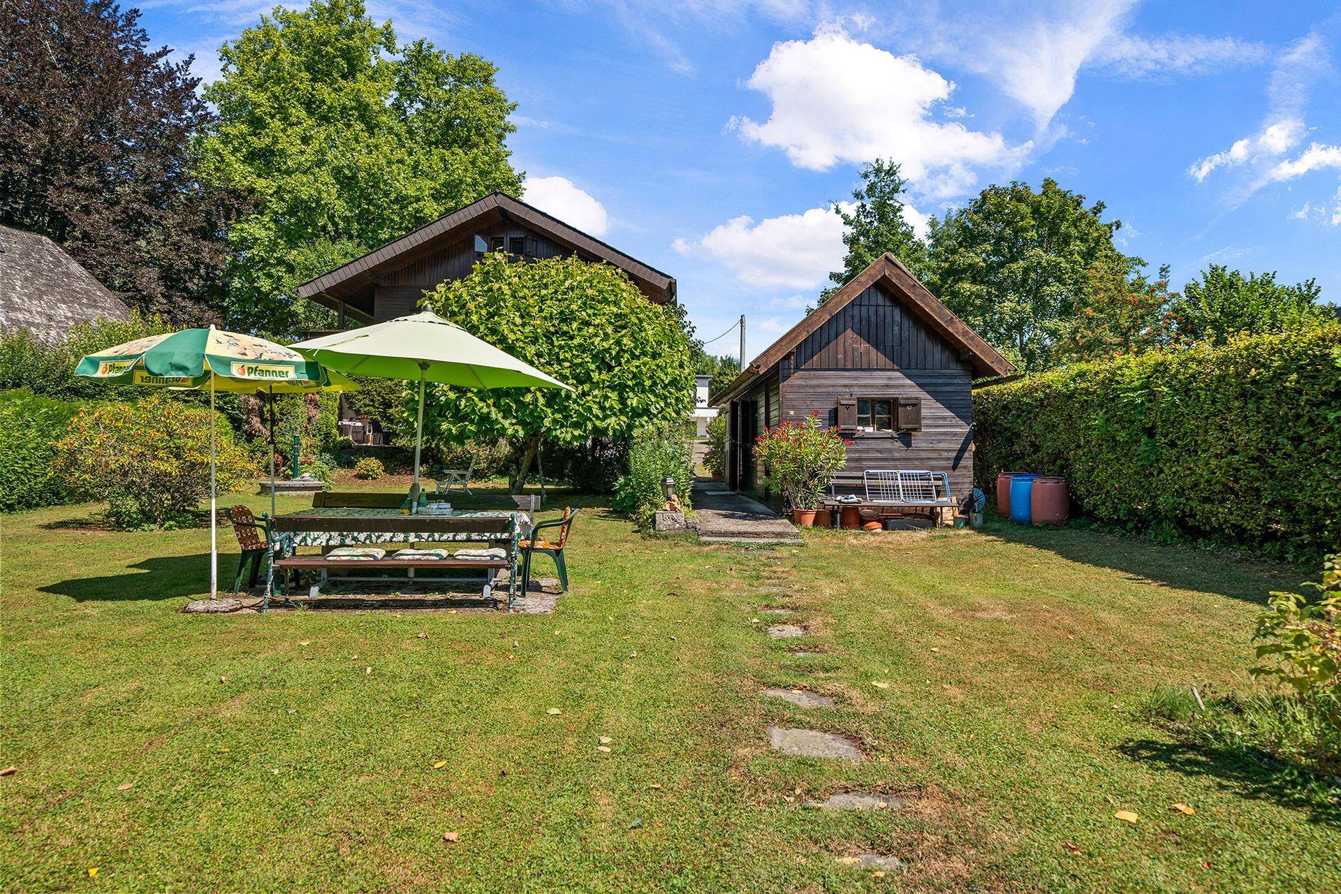 Gepflegter Garten mit Rasen, Sitzbereich und einem charmanten Holzhaus im Hintergrund.