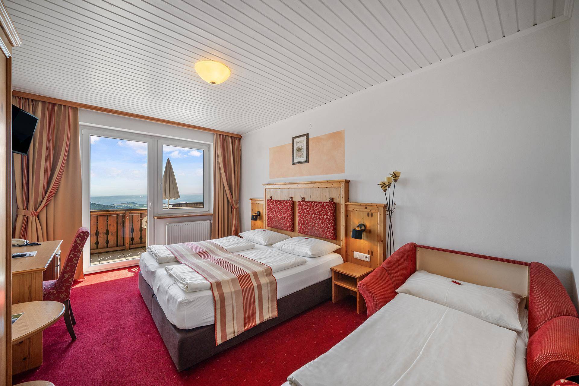 Gemütliches Schlafzimmer mit Doppelbett, zusätzlichem Schlafsofa und Zugang zu einem Balkon mit Weitblick.