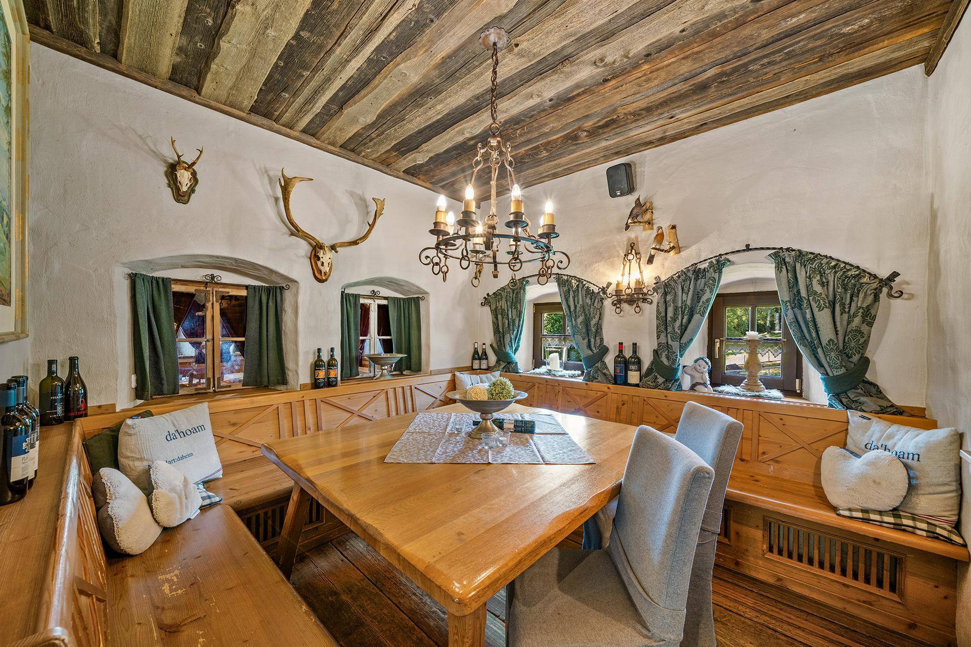 Gemütlicher Essbereich im Landhausstil mit Holztisch, Eckbank und Hirschgeweih-Dekoration an den Wänden.