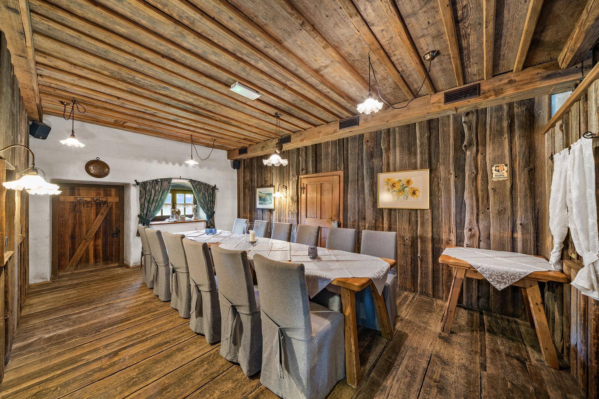 Langer Esstisch in einem rustikalen Raum mit Holzwänden und Holzboden, ideal für Feierlichkeiten.