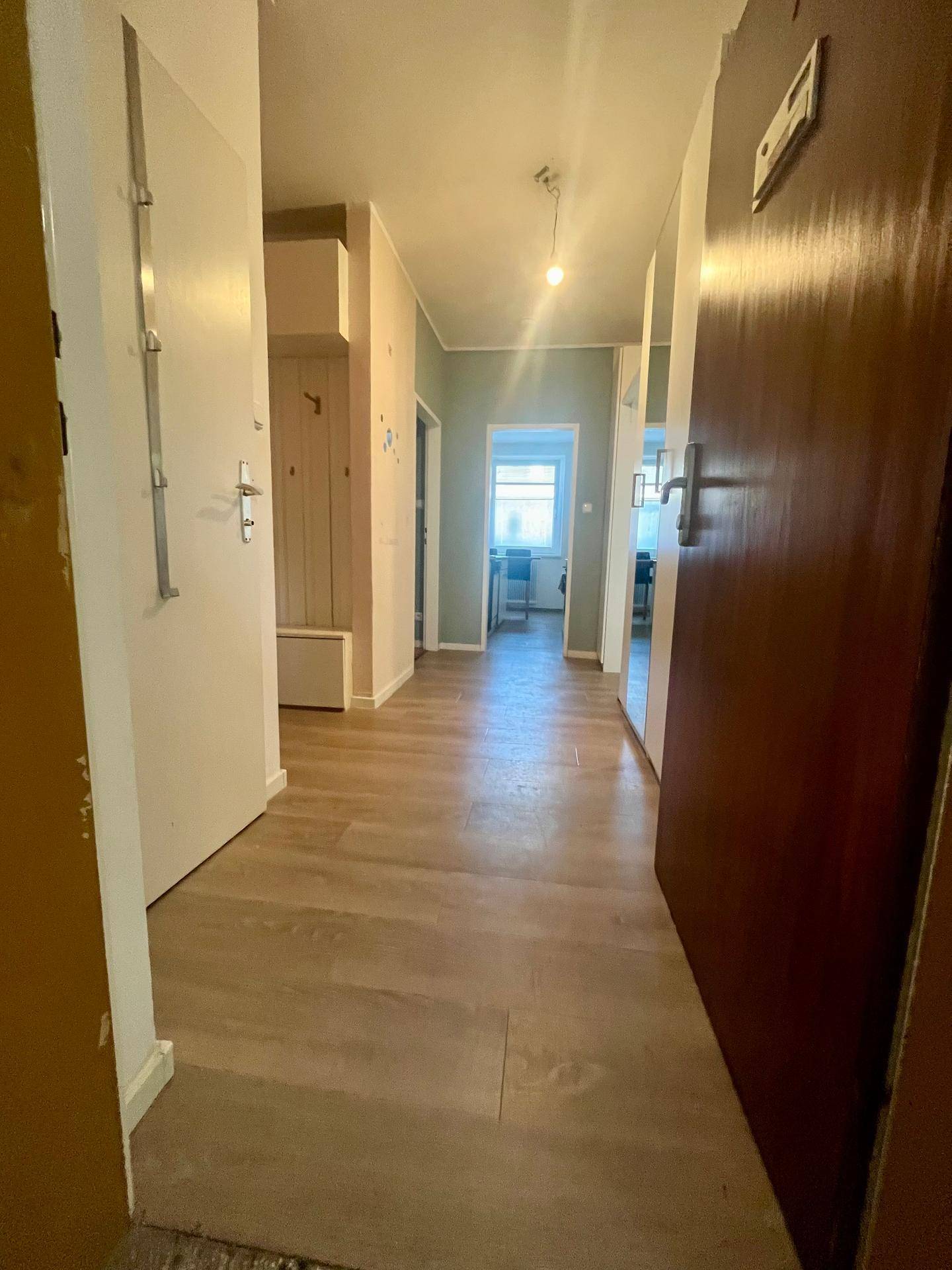 Langer Flur mit Laminatboden, der verschiedene Räume der Wohnung miteinander verbindet.