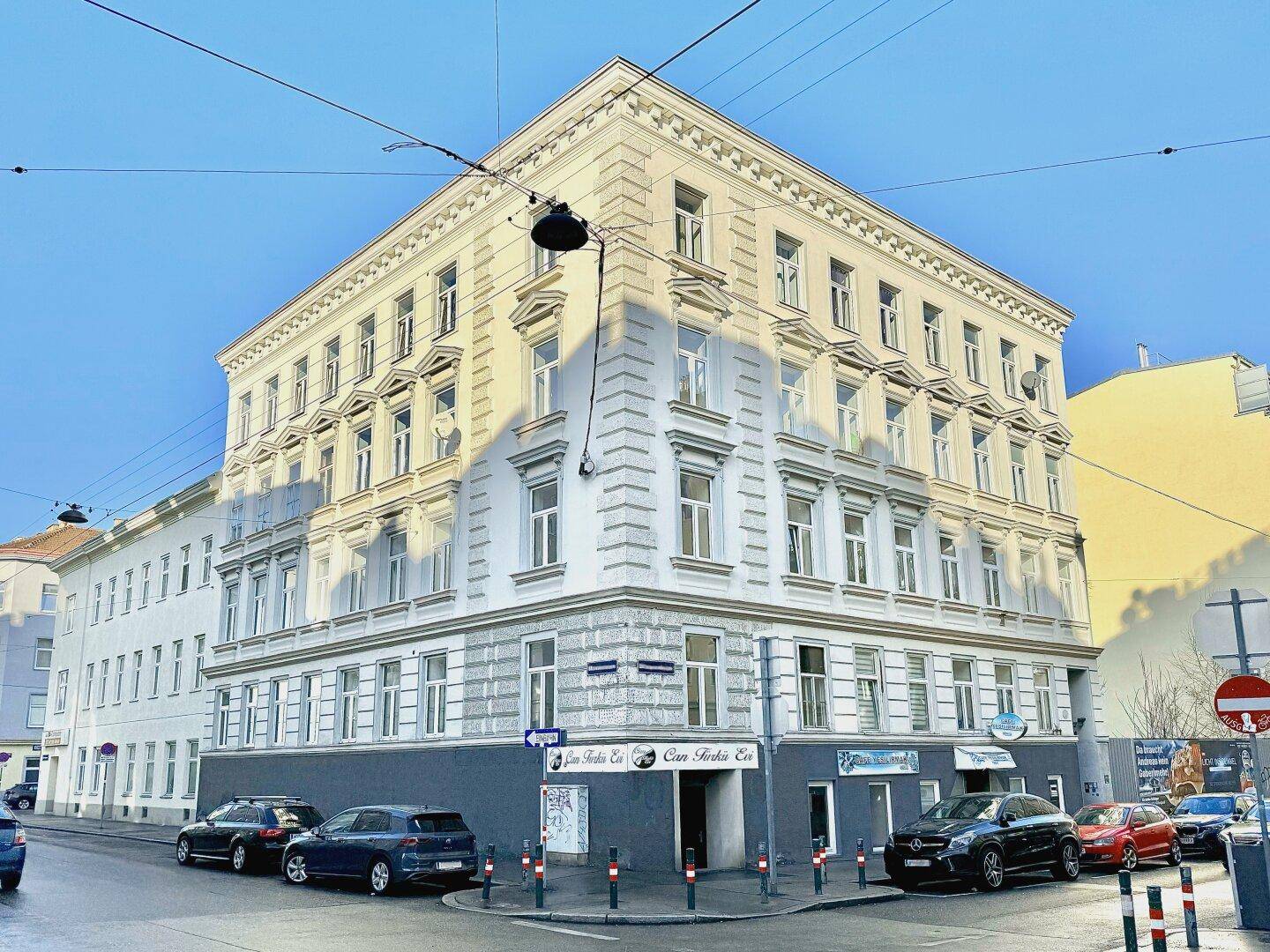Historisches Eckgebäude mit klassischer Fassade und vielen Fenstern in urbaner Umgebung.