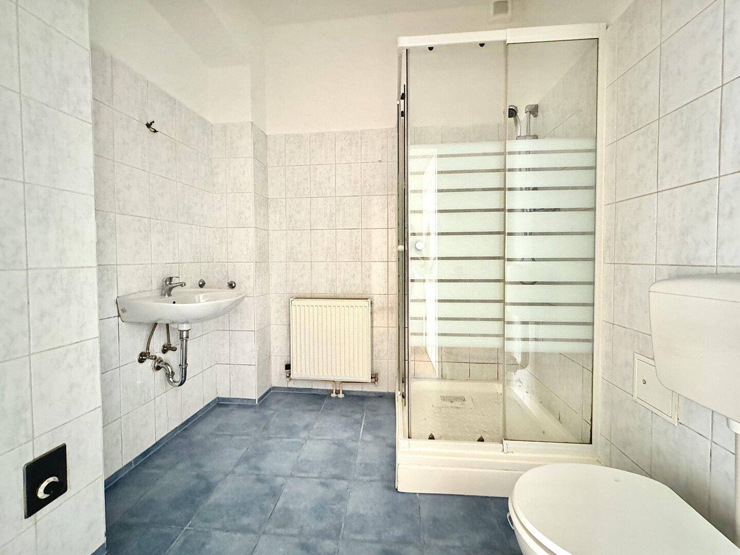 Funktionales Badezimmer mit Dusche, Waschbecken und WC, ausgestattet mit hellblauen Fliesen.