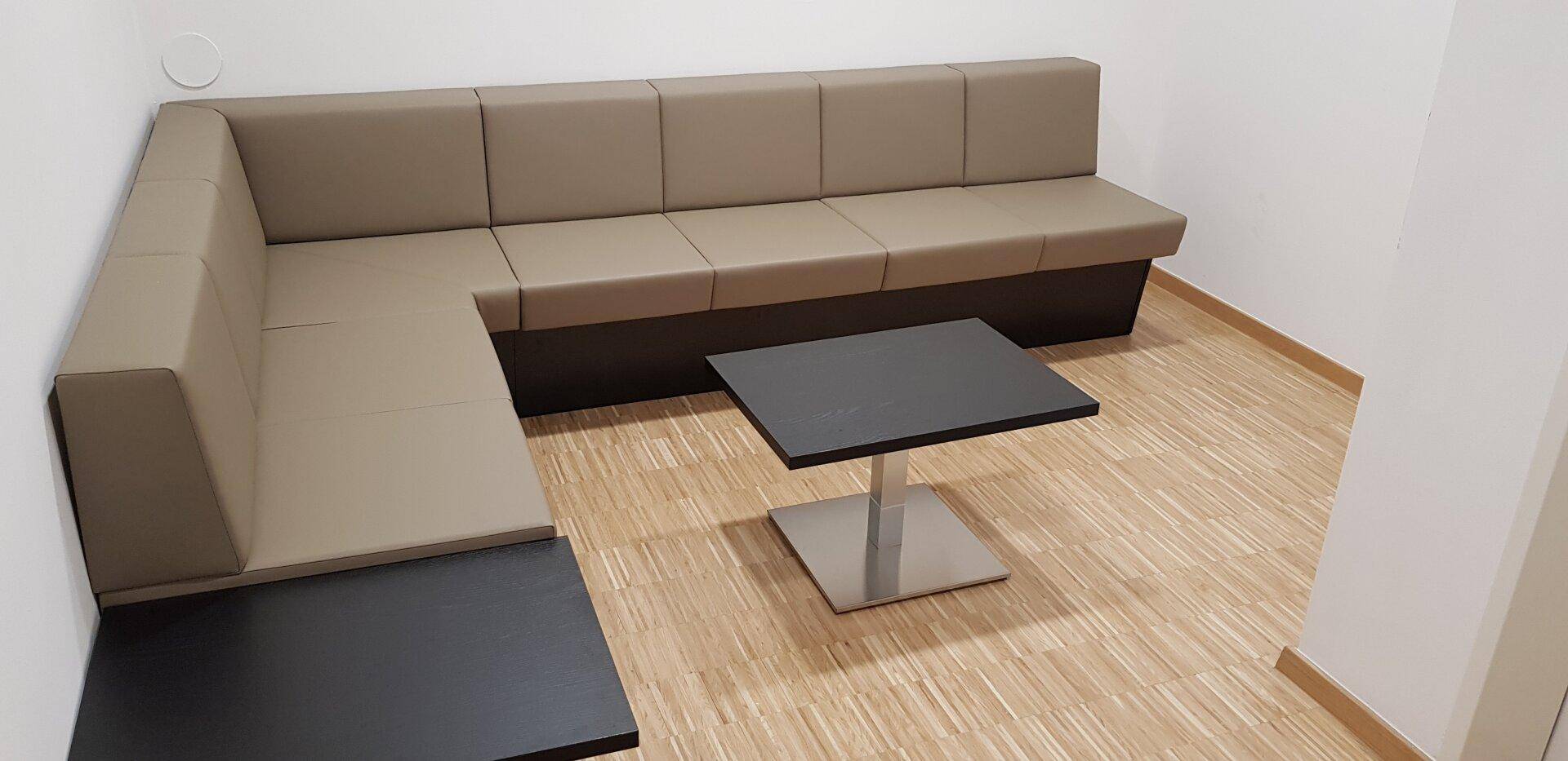 Gemütlicher Loungebereich mit beigefarbenem Ecksofa und einem modernen schwarzen Couchtisch.