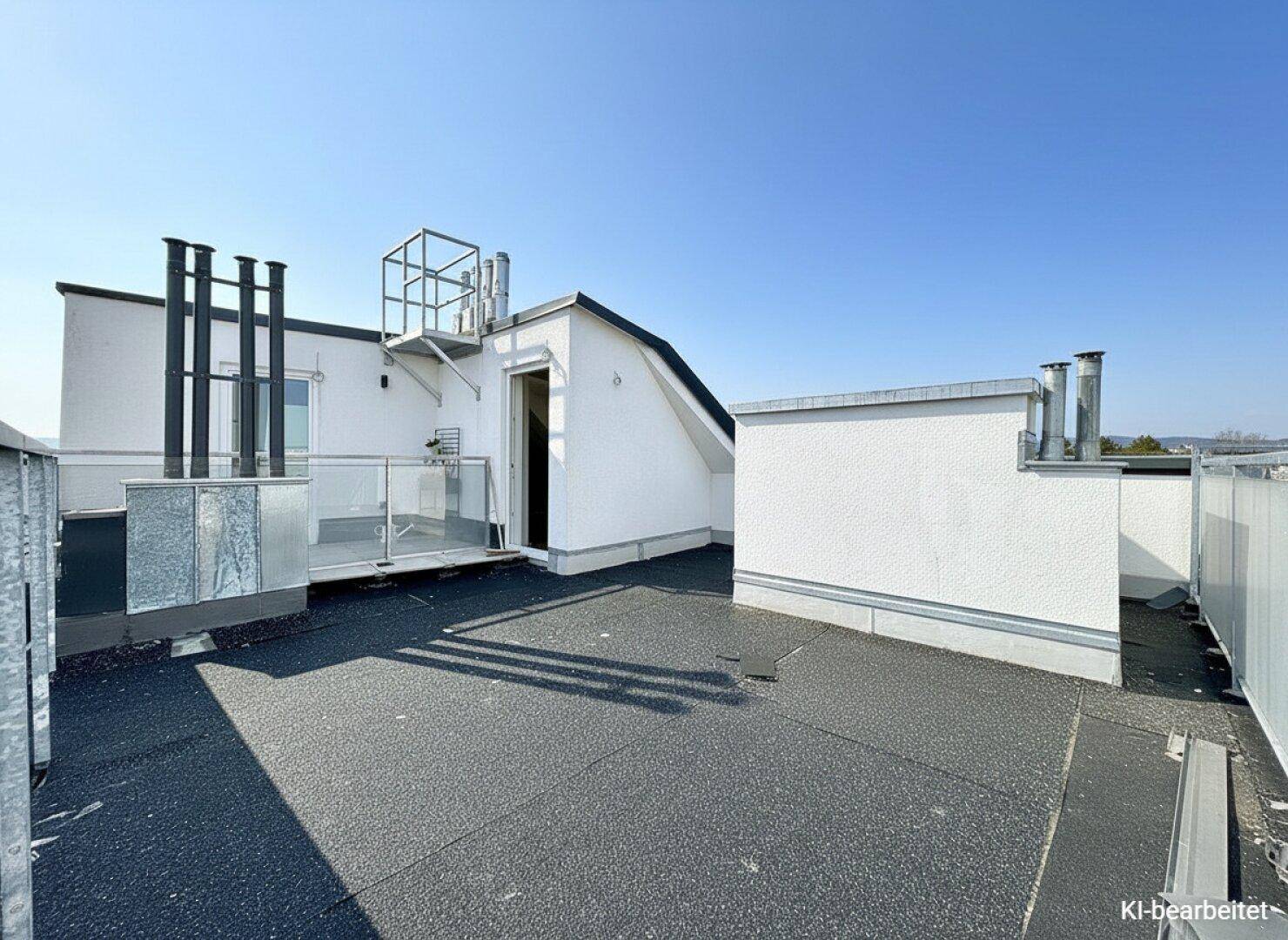 Unfertige Dachterrasse mit Bitumenbelag und Zugang zum Gebäude, bereit für die Endgestaltung.