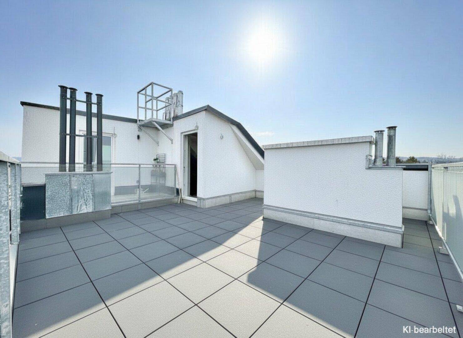 Geräumige Dachterrasse mit Fliesenboden und Zugang zum Gebäude, ideal für Entspannung im Freien.