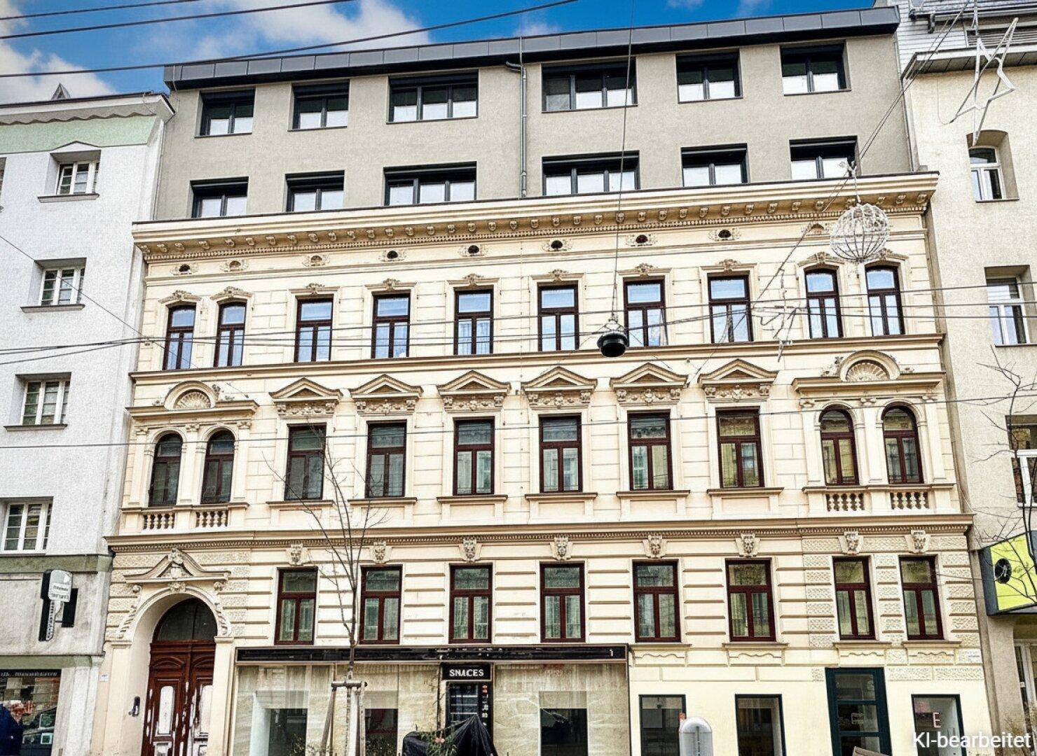 Historische Fassade eines Altbaus mit eleganten Verzierungen und modernen Dachaufbauten.