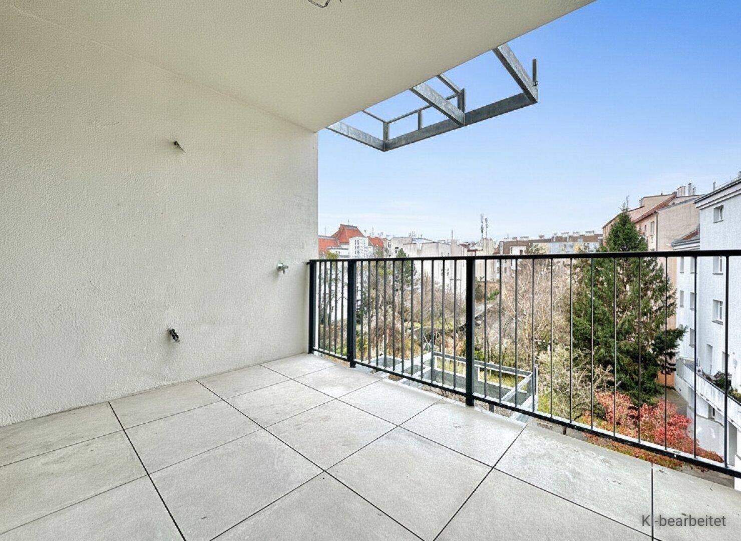 Heller Balkon mit Fliesenboden und Blick ins Grüne, ideal für entspannte Stunden im Freien.