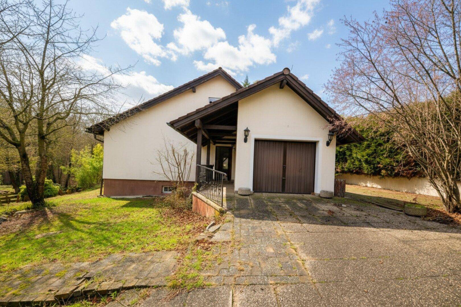 Vorderansicht des Hauses mit integrierter Garage, Zufahrt und gepflegtem Vorgarten.