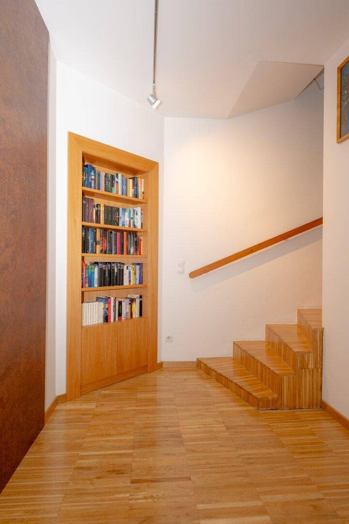 Flur mit Holztreppe, Holzboden und integriertem Bücherregal.