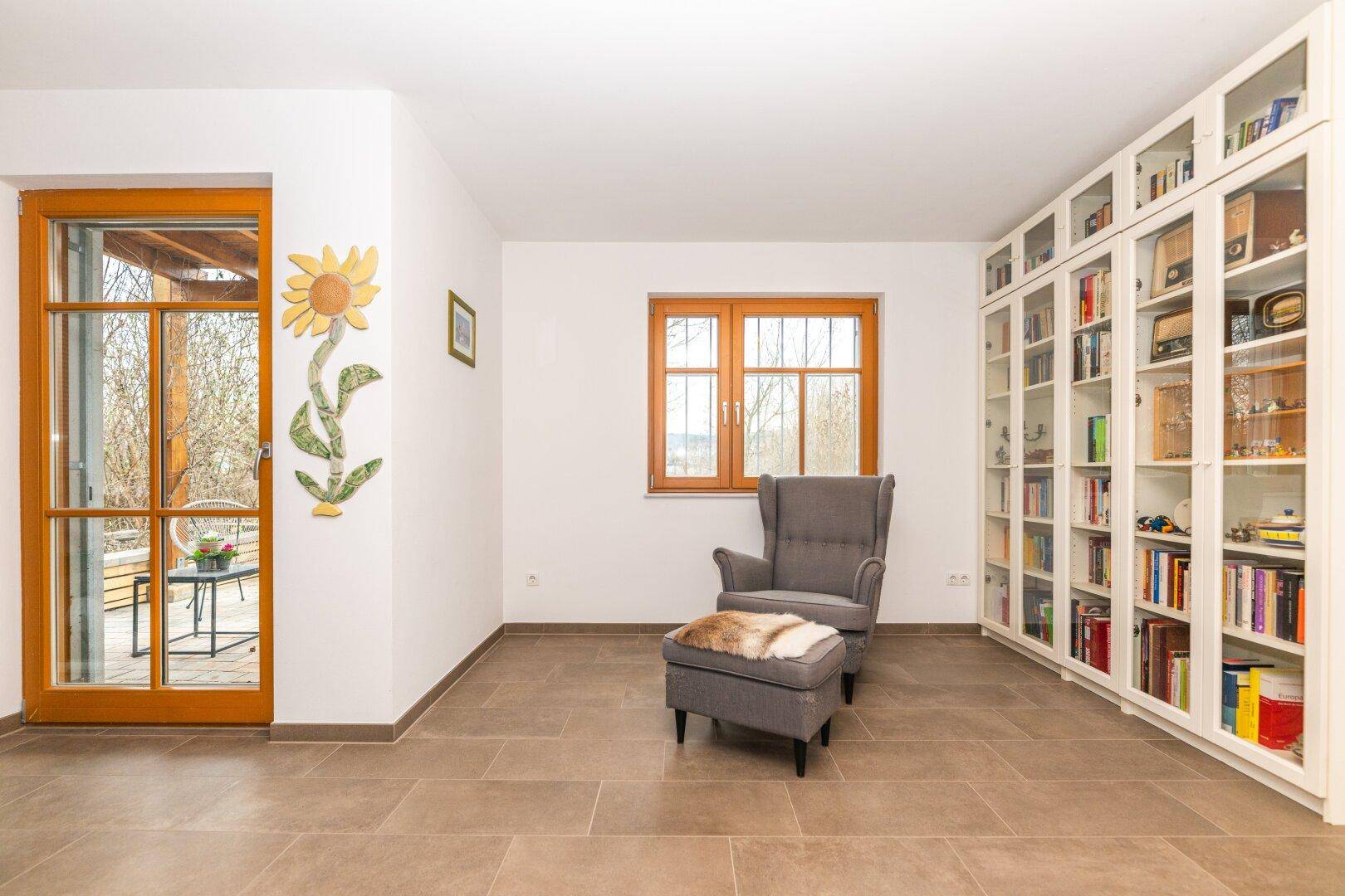 Heller Eingangsbereich mit Fliesenboden und großem Bücherregal an der Wand.