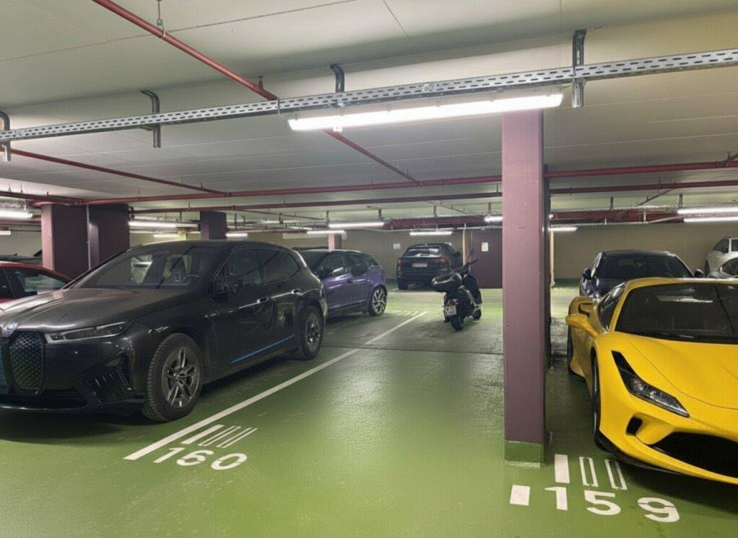 Helle Tiefgarage mit verschiedenen Fahrzeugen und klarer Bodenmarkierung für die Parkplätze.