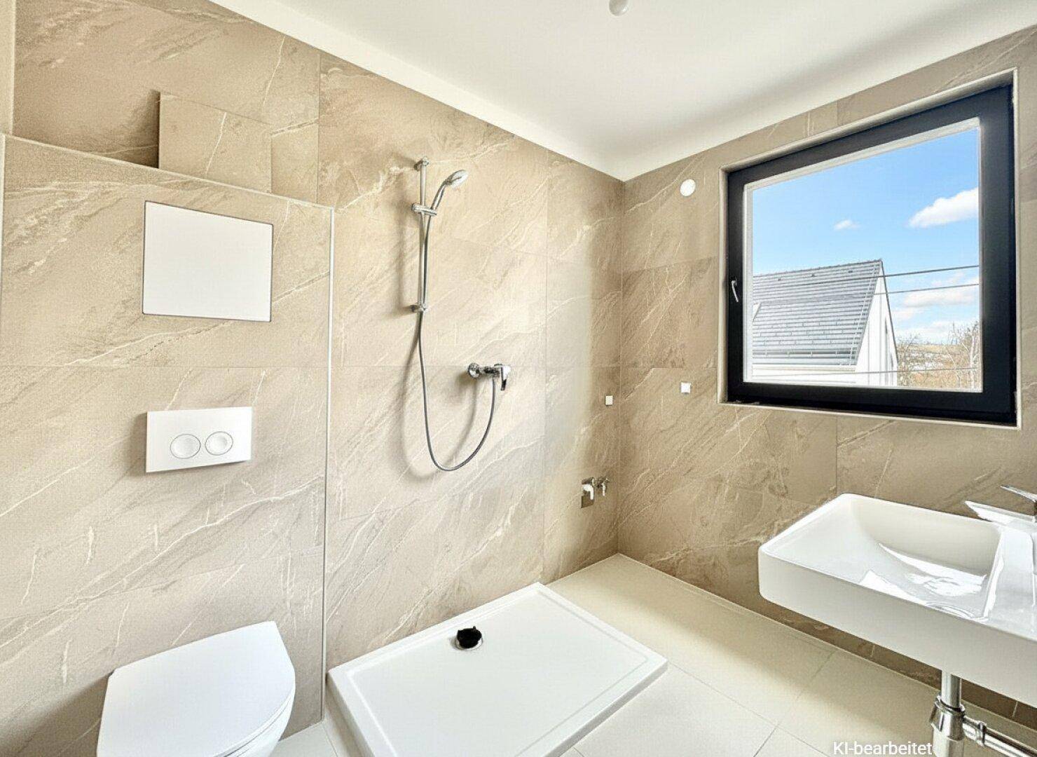 Modernes Badezimmer mit beigefarbenen Fliesen, Dusche, wandhängendem WC und Fenster für Tageslicht.