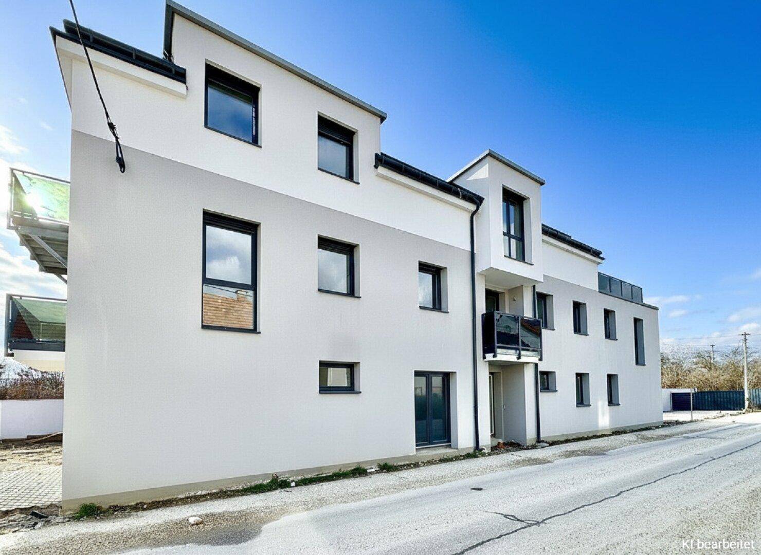 Moderne Wohnhausfassade mit klaren Linien und großen Fenstern in einer ruhigen Umgebung.