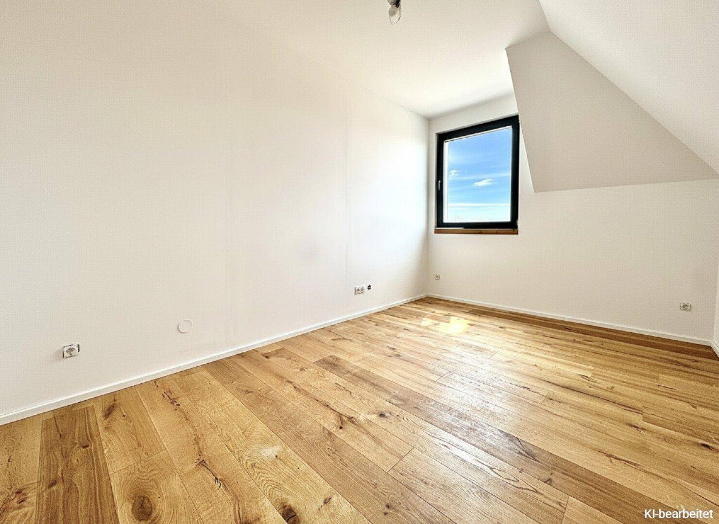Lichtdurchflutetes Zimmer mit Dachschräge und Holzparkett, ideal als Schlaf- oder Arbeitszimmer.