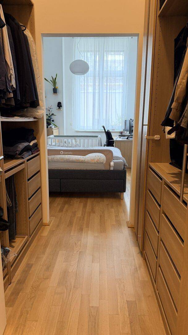 Begehbarer Kleiderschrank mit Holzregalen und Schubladen, der zum Schlafzimmer führt.