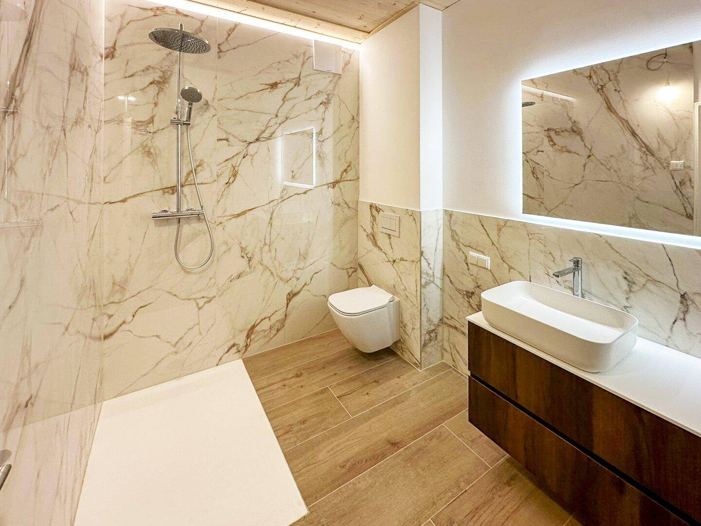 Modernes Badezimmer mit luxuriösen Marmorfliesen, begehbarer Dusche und elegantem Waschtisch.
