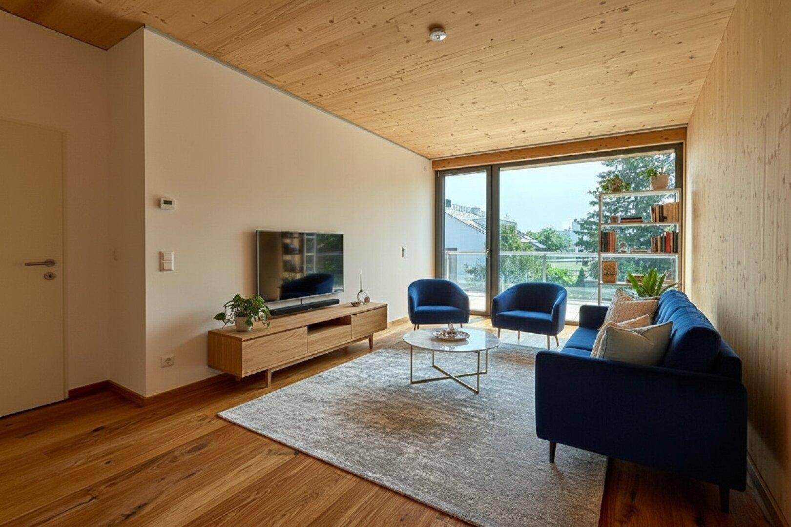 Gemütliches Wohnzimmer mit Holzboden, Holzdecke, blauen Möbeln und Zugang zum Balkon.