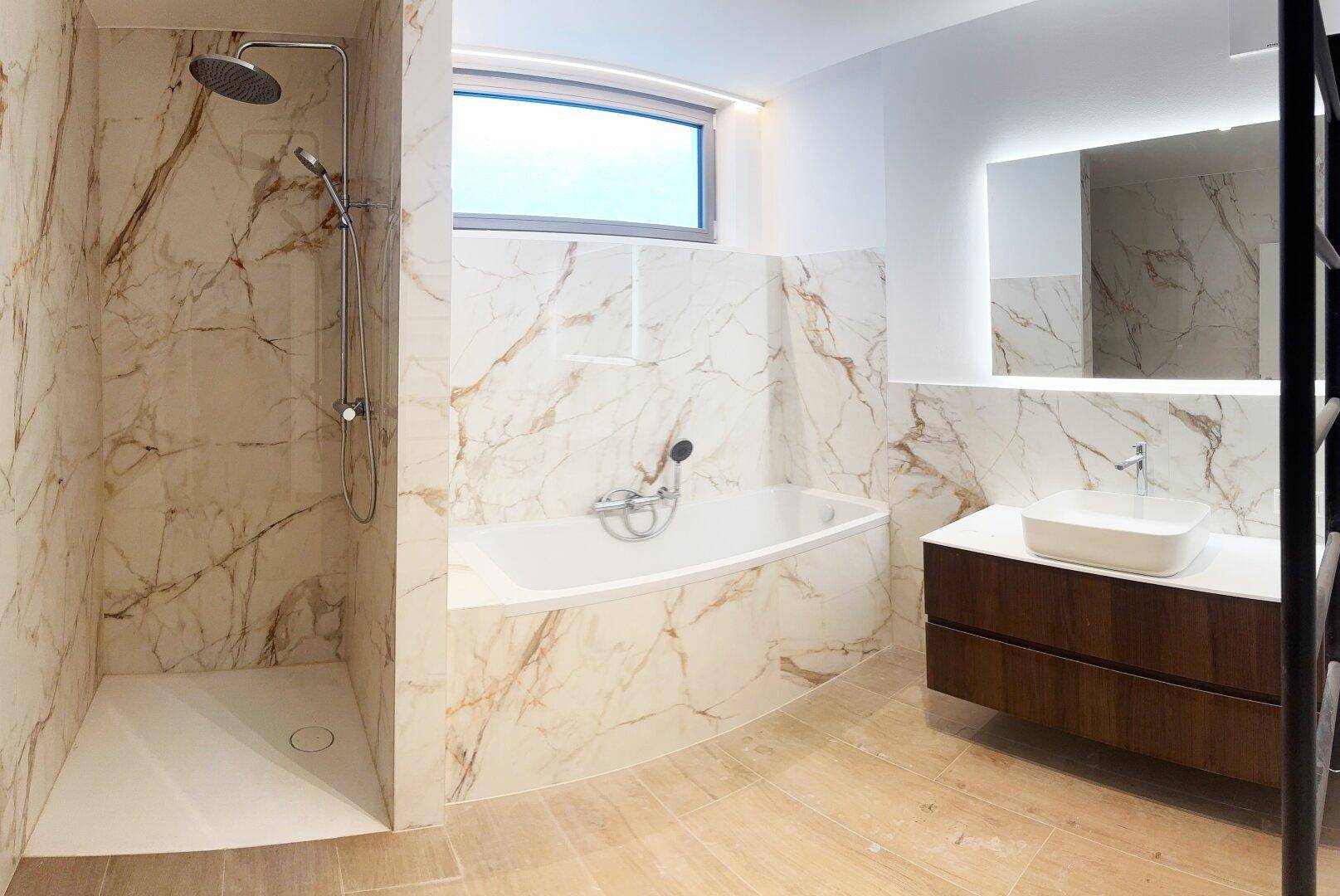 Helles Badezimmer mit stilvollen Marmorfliesen, integrierter Badewanne und geräumiger Walk-in-Dusche.