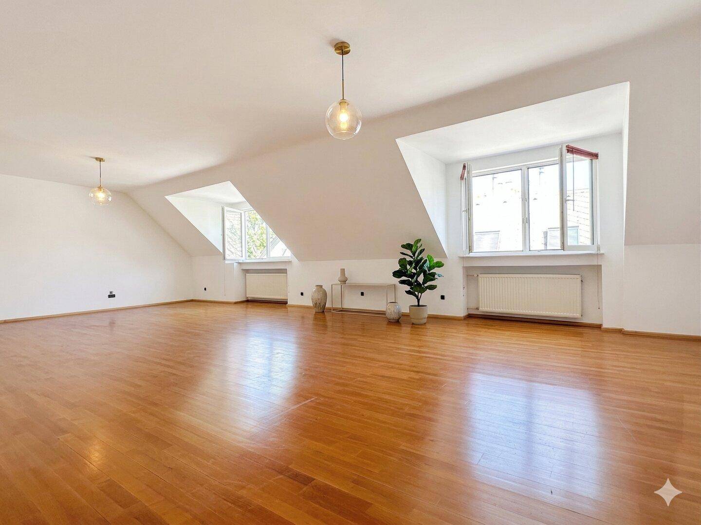 Geräumiger Dachbodenraum mit Holzboden und schrägen Wänden, ideal für ein Studio.
