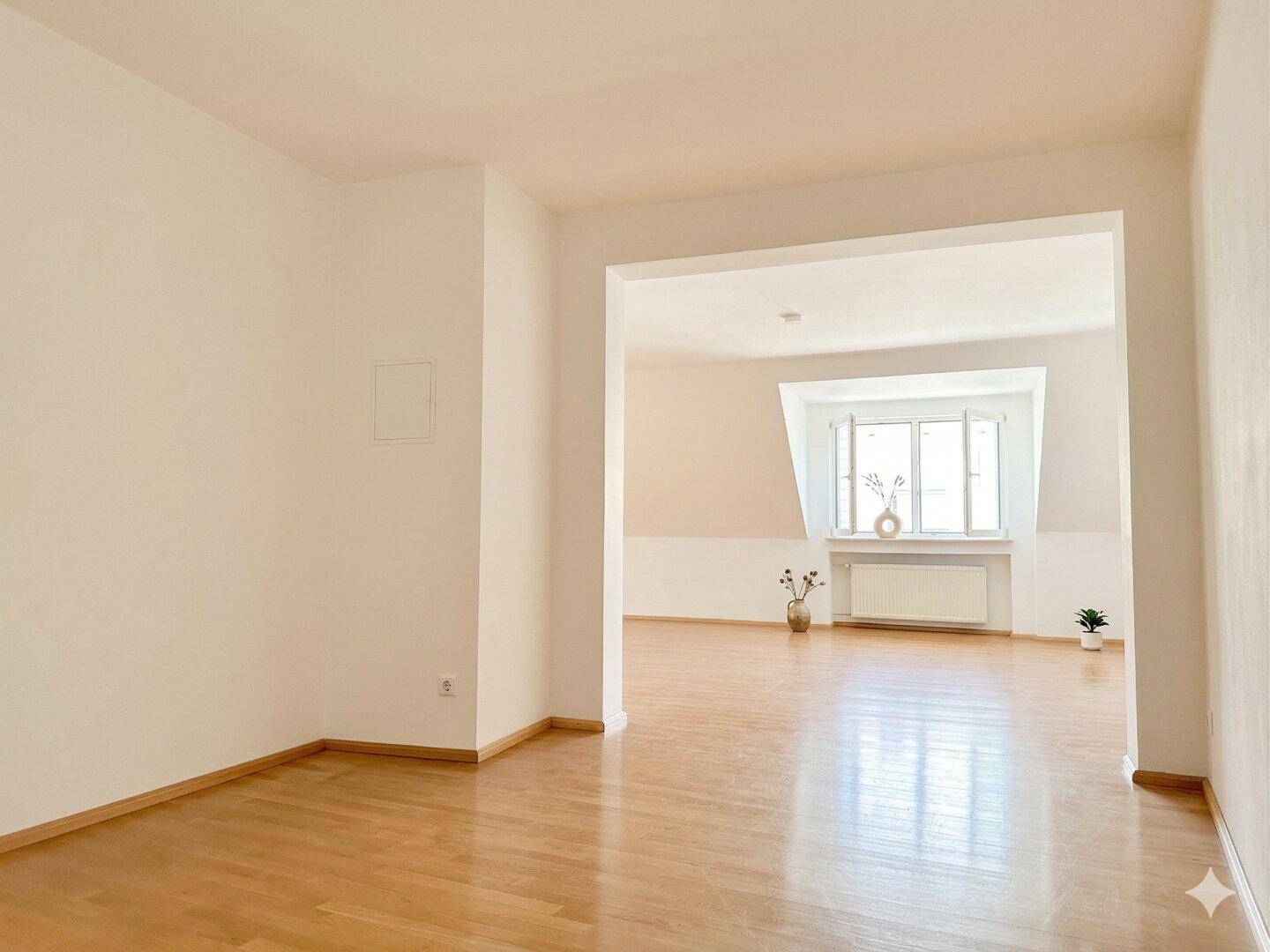 Heller Dachbodenraum mit Holzboden und offenem Durchgang zu einem weiteren Bereich.