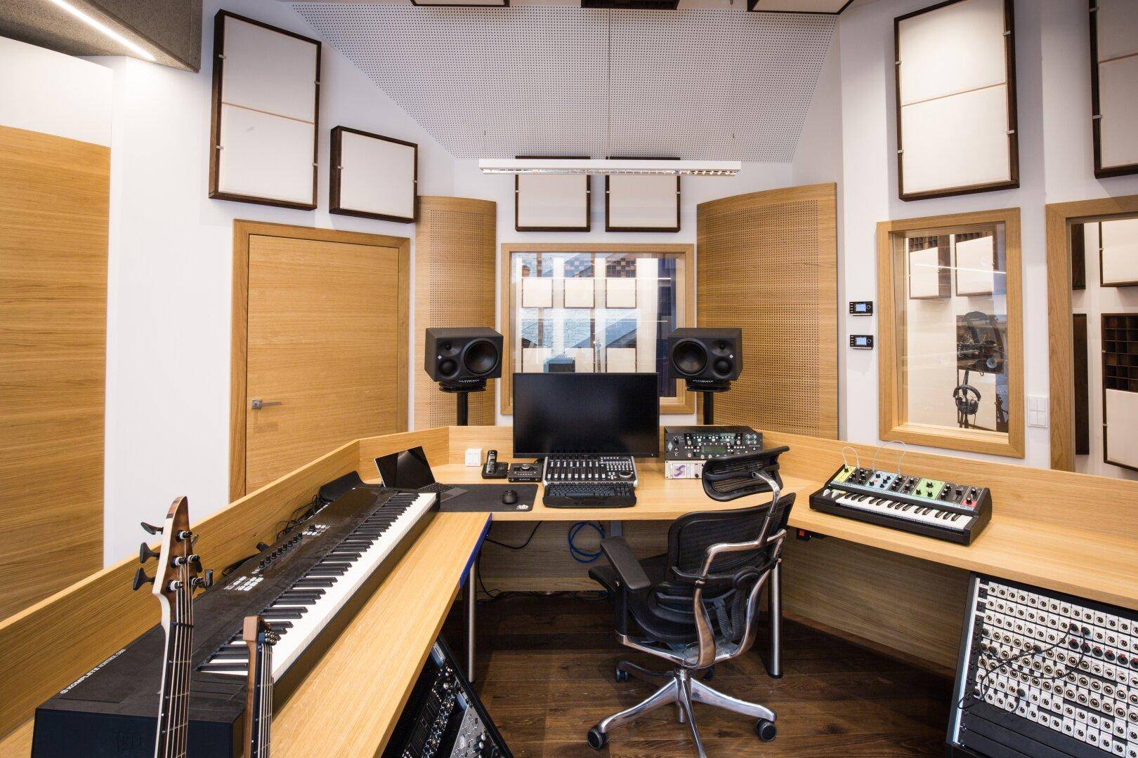 Kontrollraum eines Musikstudios mit Mischpult, Keyboards und professionellen Studiomonitoren.