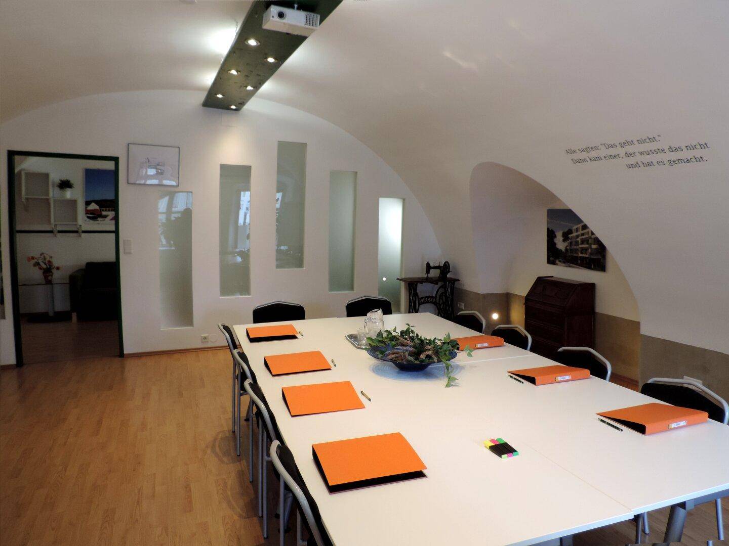 Geräumiger Konferenzraum mit gewölbter Decke, modernem Lichtdesign und Holzboden für Besprechungen.