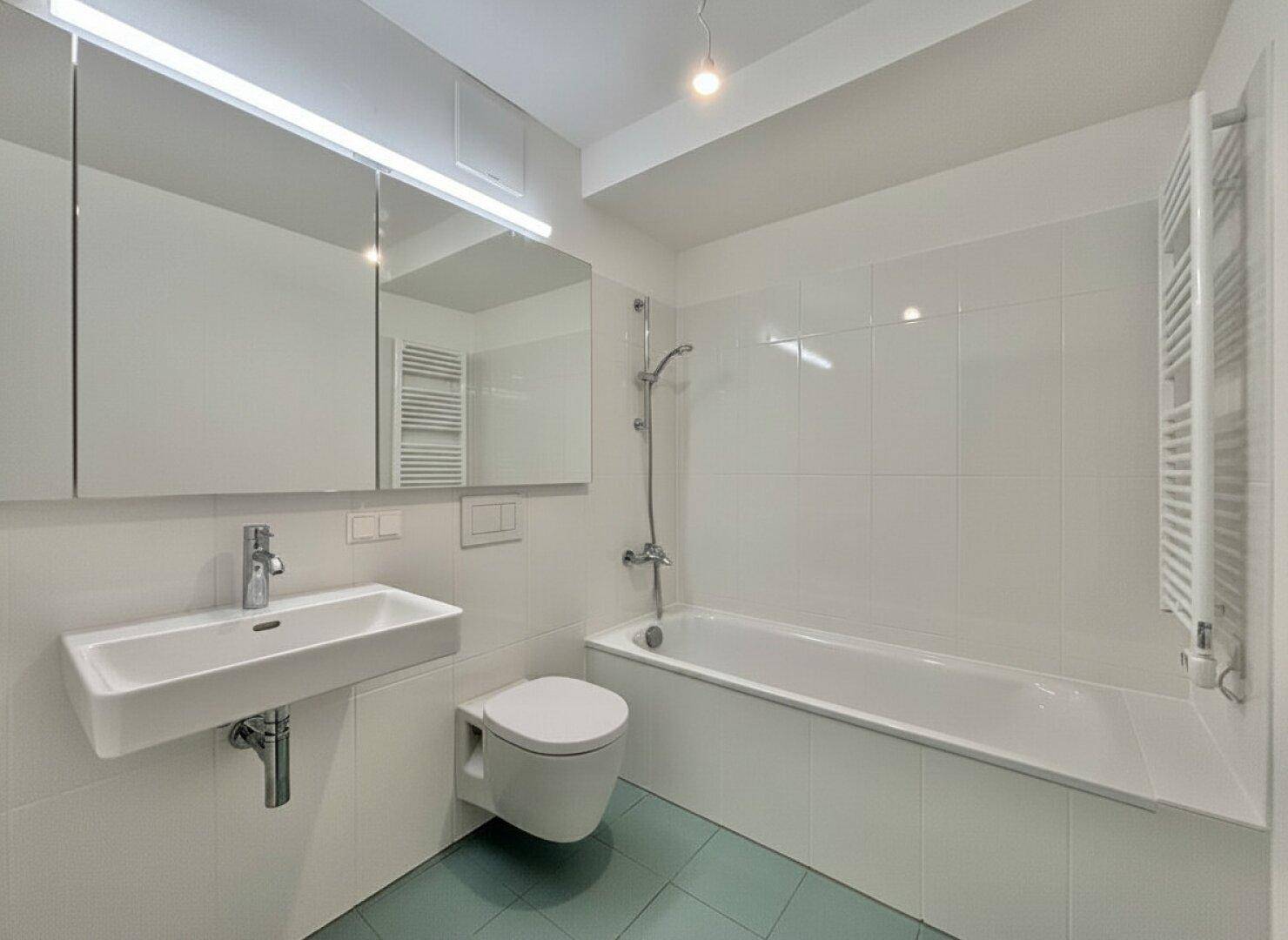 Modernes Badezimmer mit Badewanne, Waschbecken, Wand-WC und beheiztem Handtuchhalter.