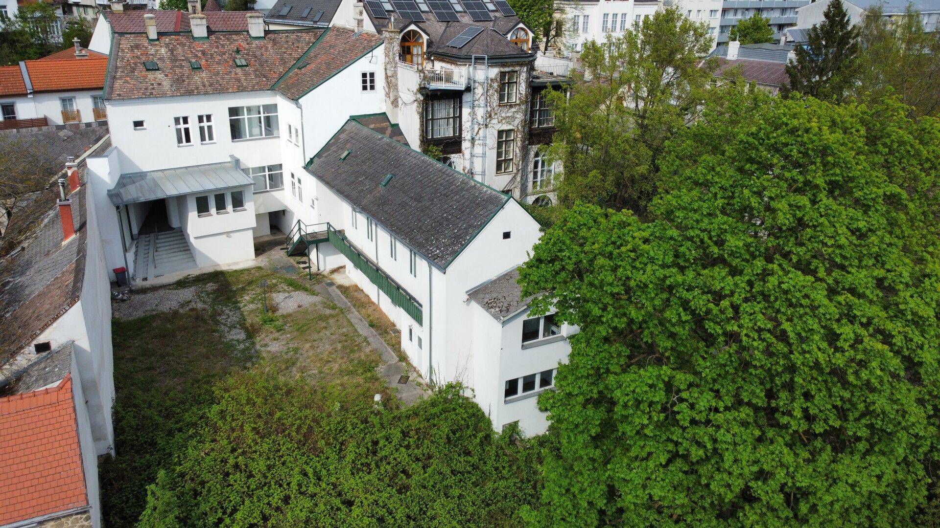 Luftaufnahme eines Wohngebiets mit mehreren weißen Gebäuden und viel Grünfläche.