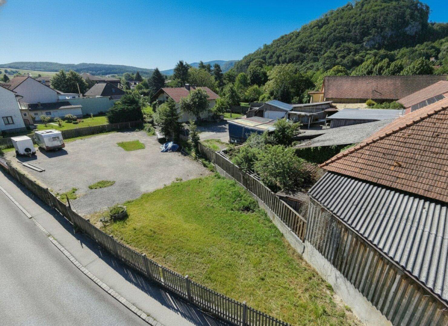 Luftaufnahme eines unbebauten Grundstücks mit Rasenfläche und Blick auf die umliegende Hügellandschaft.