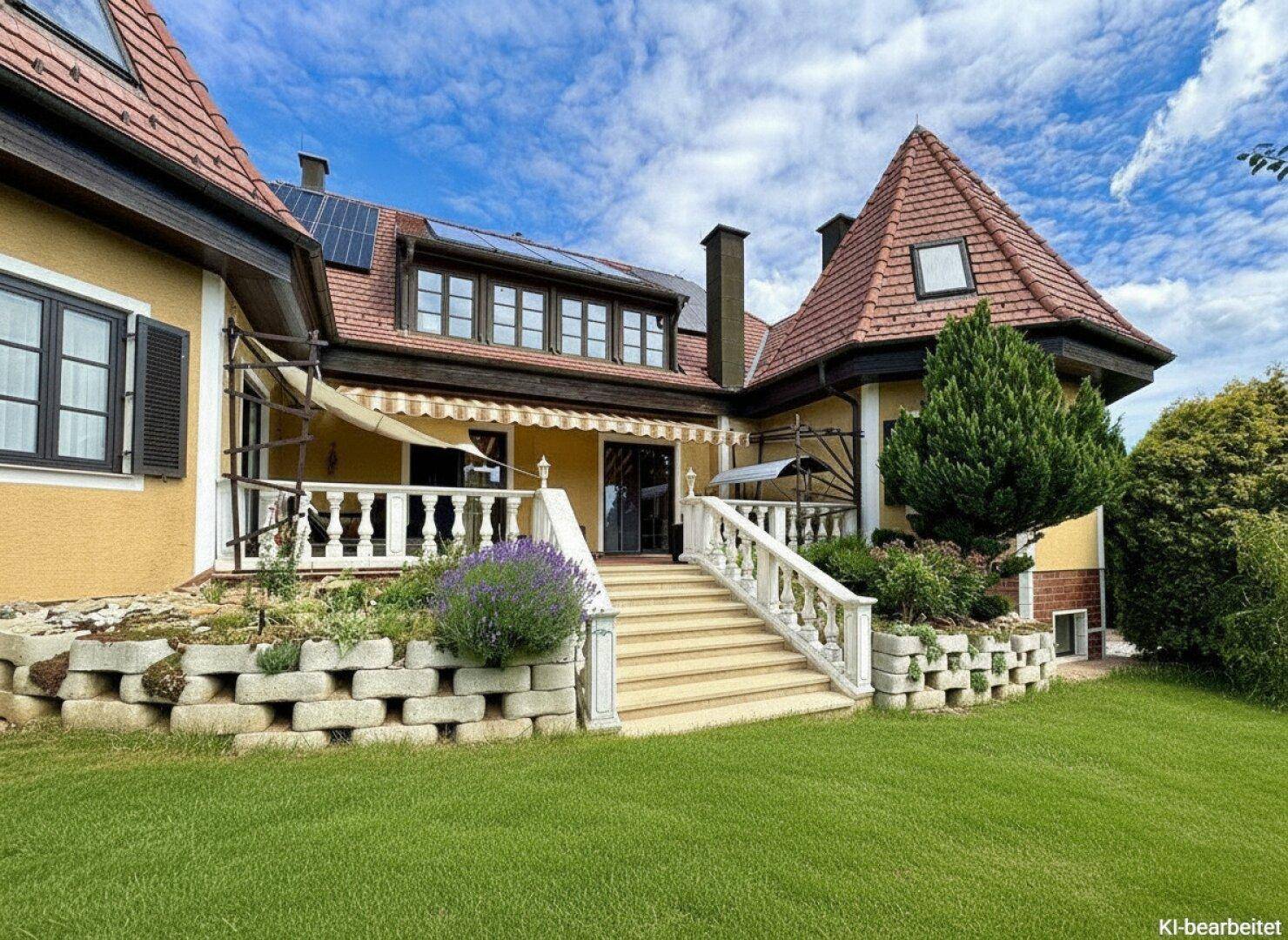 Rückansicht des Hauses mit Terrasse, Treppe zum Garten und Solarpaneelen auf dem Dach.
