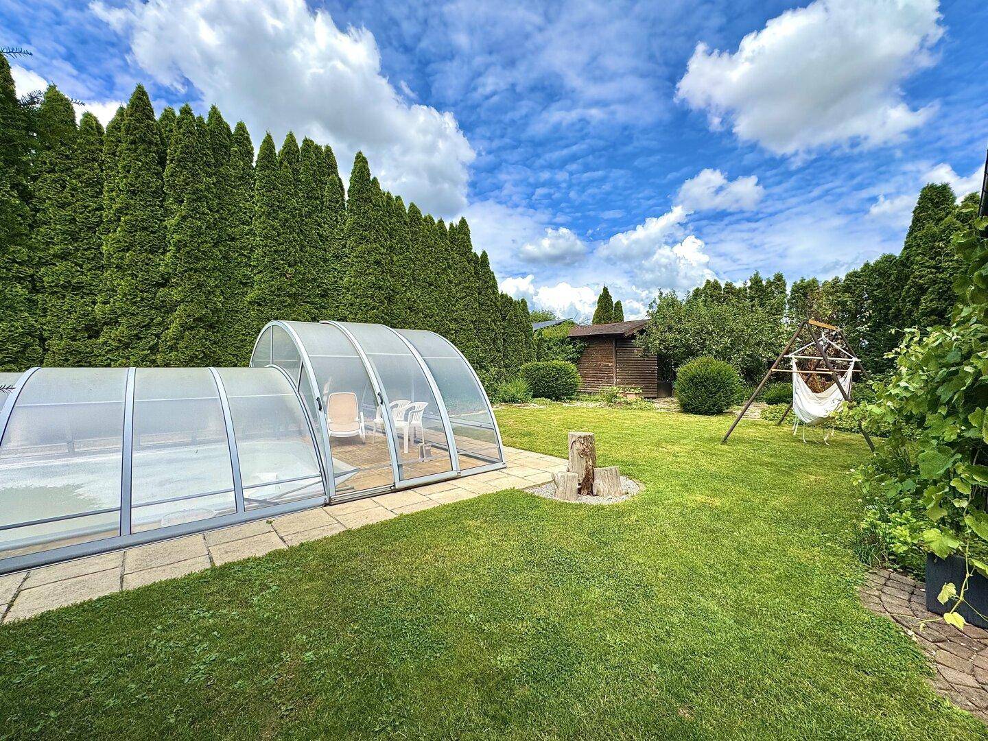Großer Gartenbereich mit überdachtem Pool, Gartenhaus und viel Grün.
