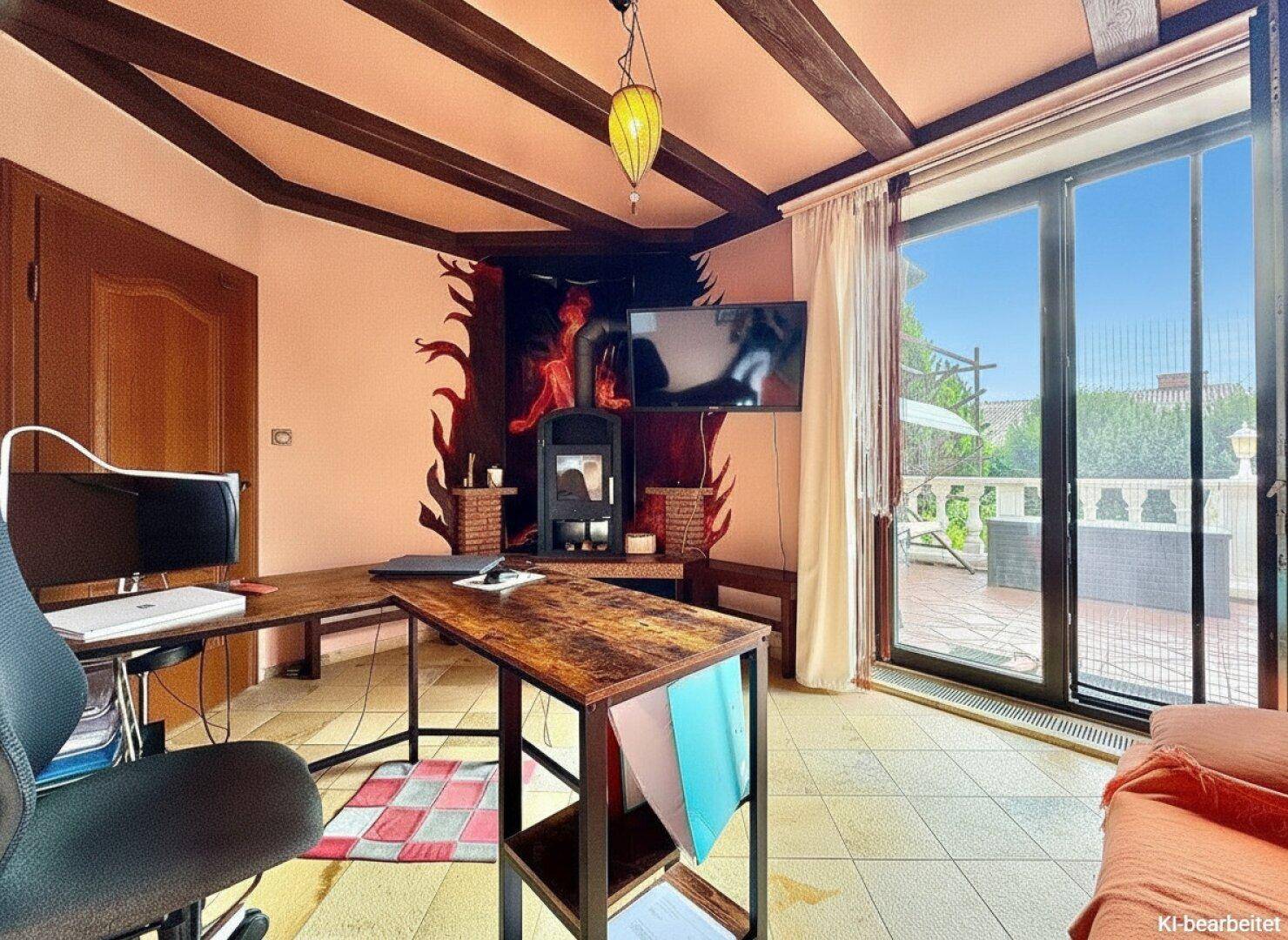 Arbeitszimmer mit Holzbalkendecke, Kamin und Zugang zur Terrasse.