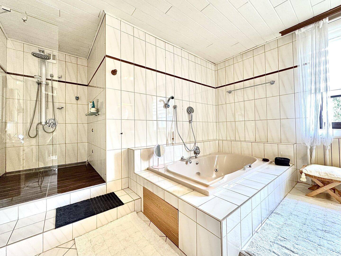 Großes Badezimmer mit Badewanne, Dusche und weißen Fliesen.