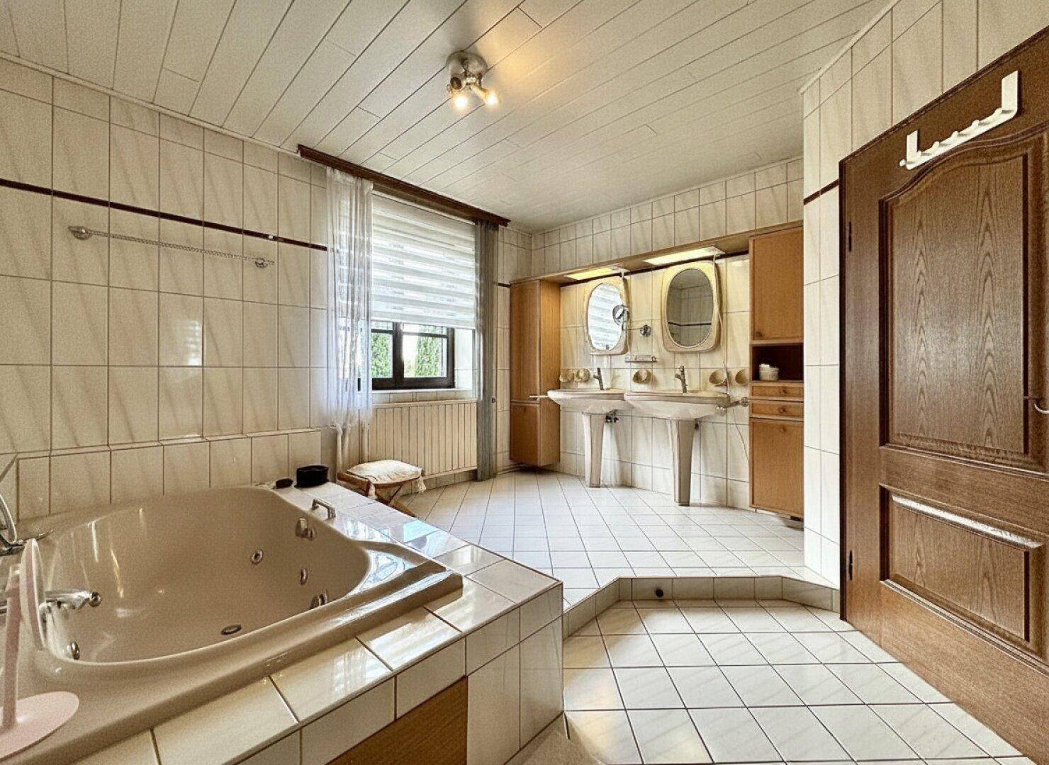 Geräumiges Badezimmer mit Whirlpool-Badewanne, Doppelwaschbecken und Fenster.