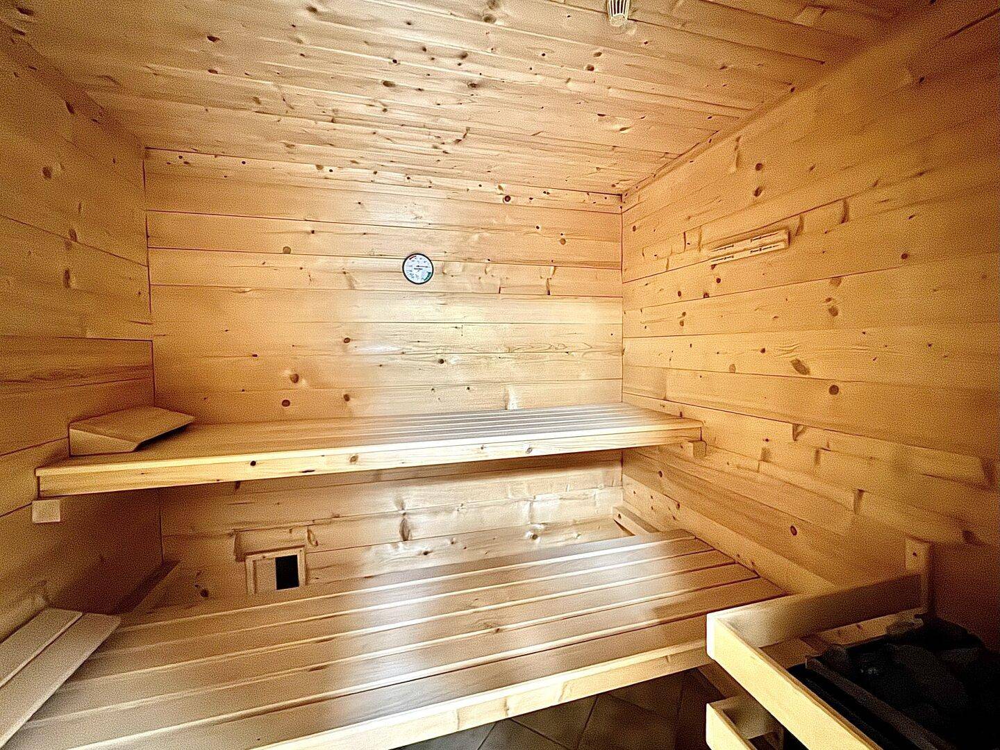 Holzvertäfelte Sauna mit Sitzbänken für Entspannung und Wellness.